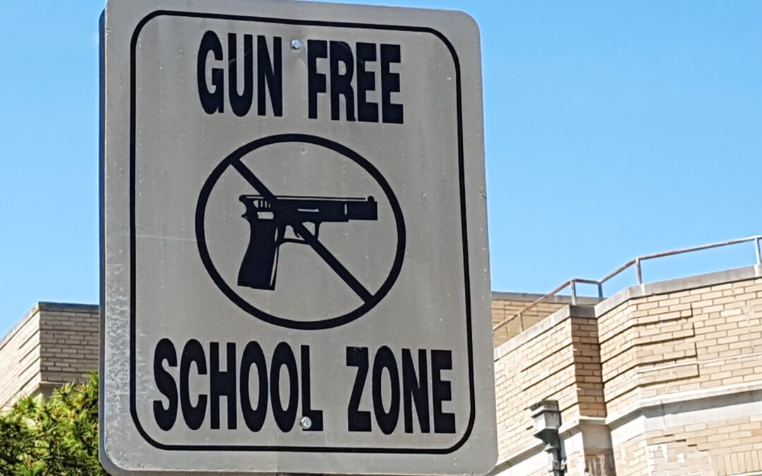 A sign announces a "Gun Free School Zone" for gun detection in schools blog.